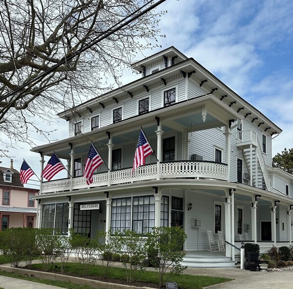 A two-story building with a balcony, American flags, and a sign reading 'BELVEDERE.' - Quintessential Cape May (Cape May)