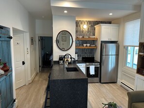 A modern kitchen with a central island, stainless steel appliances, and a view to the outside. - Quintessential Cape May (Cape May)