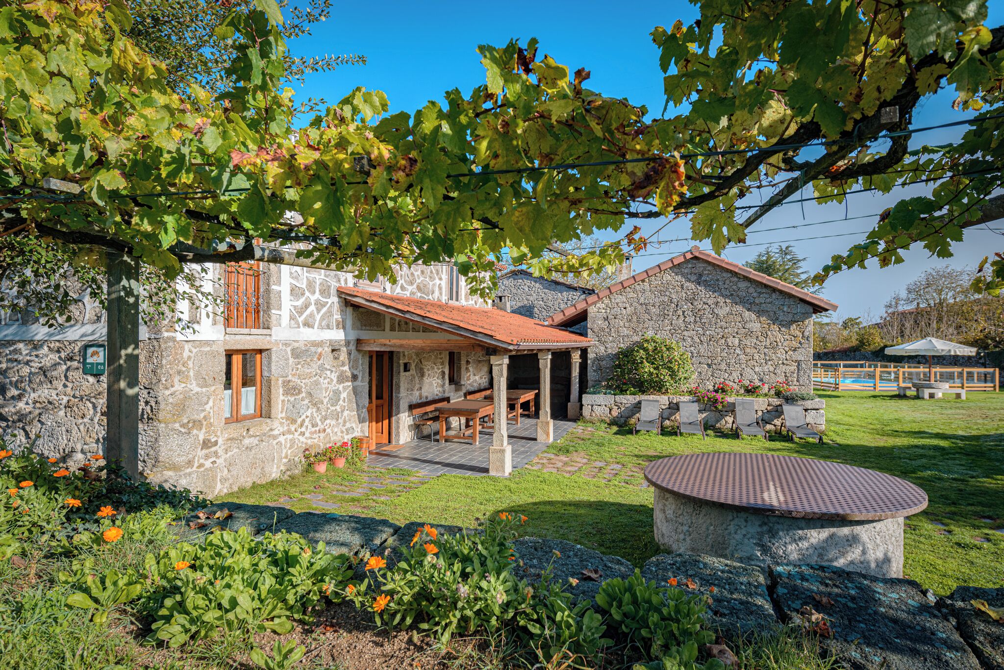A stone house with a patio, outdoor seating, and a garden with flowers.