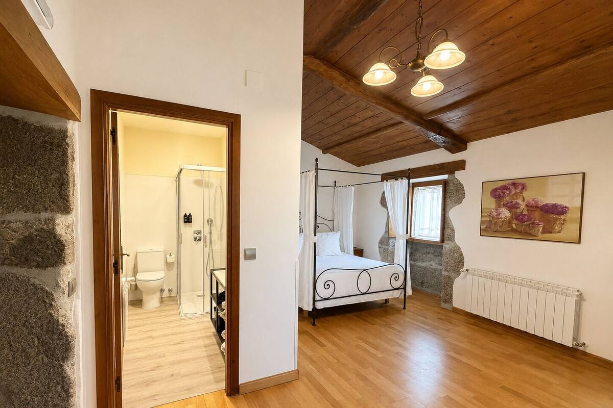 A bedroom with a four-poster bed, a wooden ceiling, and a stone wall.
