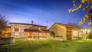 A stone house with a well-maintained lawn and a patio area. - Casa das Xacias (A Airoá)