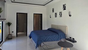 Une chambre moderne avec un grand lit, une table de chevet, une petite table ronde et un plafond au design original.