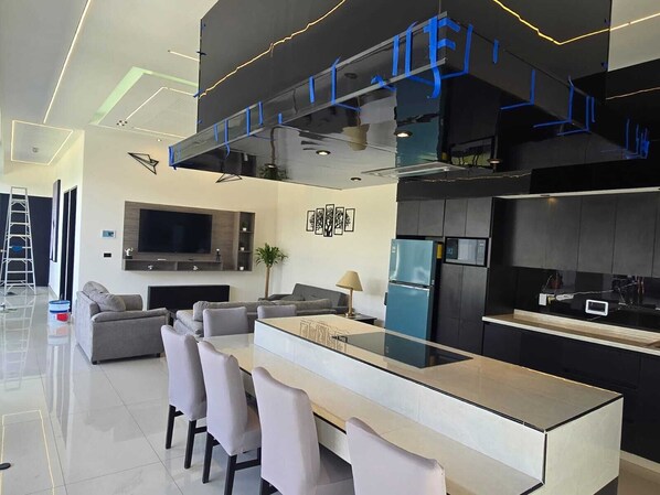 A modern kitchen with a central island, built-in appliances, and a flat-screen TV.