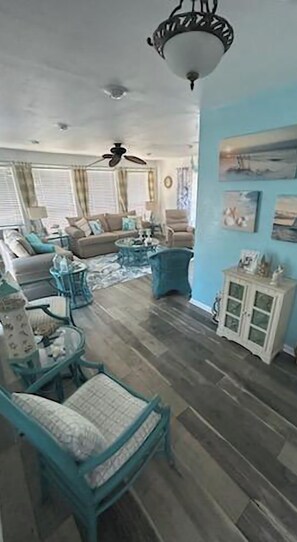A living room with a sofa, chairs, a coffee table, a ceiling fan, and a cabinet with pictures. - Surfside 2 blocks from Beach-Jetty-Splash pad 2 bdrm 3 bath (Freeport)
