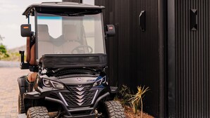 A black golf cart parked in front of a building with a corrugated metal exterior. - Cozy 2-bedroom villa in serene Monteverde with Pool and AC (Monteverde)