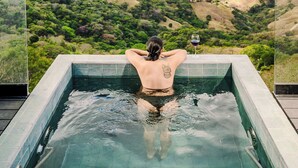 A person relaxing in a hot tub with a scenic view of hills and valleys. - Cozy 2-bedroom villa in serene Monteverde with Pool and AC (Monteverde)