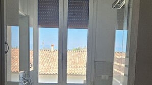 Une salle de bain avec une fenêtre, un lavabo, des toilettes et un espace douche.