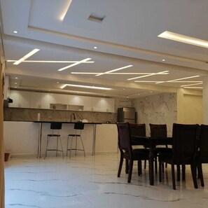 A modern kitchen with a marble countertop, stainless steel appliances, and a dining area with a marble floor and wooden chairs. - Akenza Hospitality. Pleasant family stay in a superb villa with private pool (Marrakesh)