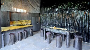 Eine moderne Bar mit Glastisch, Hockstühlen und einer Wand mit besonderer Struktur.