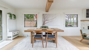 Un coin repas comprenant une table en bois, quatre chaises, un banc et une vue sur l’extérieur par le biais de fenêtres.