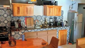 Eine Küche mit Holzschränken, ein Essbereich mit Tisch und Stühlen sowie ein Deckenventilator.