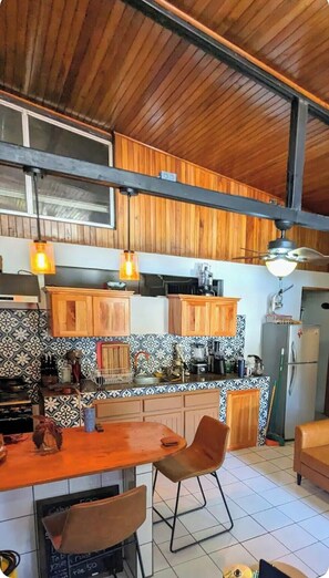 Eine Küche mit Holzschränken, ein Essbereich mit Tisch und Stühlen sowie ein Deckenventilator.