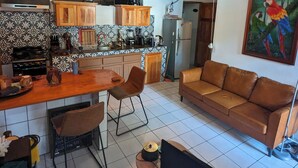 Eine Küche mit Holzausstattung, ein Essbereich mit Tisch und Stühlen, ein Sofa und ein Fernseher.