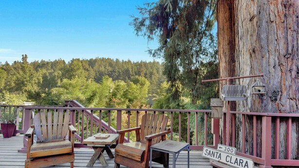 Una terraza de madera con dos sillas Adirondack, una mesita y un cartel que dice 'SANTA CLARA'.