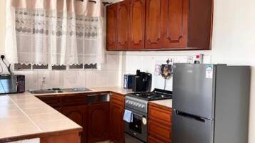 Une cuisine avec des meubles de rangement en bois, une cuisinière, un réfrigérateur et un évier.