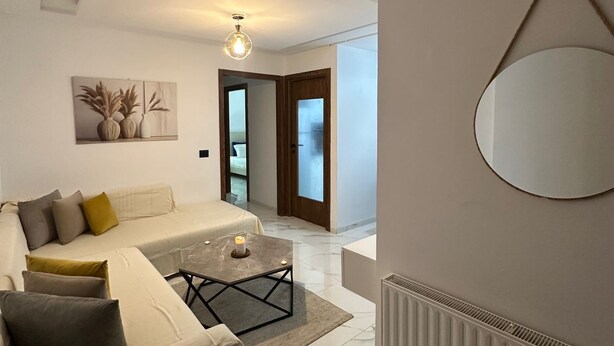 A modern bedroom with a bed, a coffee table, and a large mirror. - Exceptional Apartment Luxury and Absolute Comfort (Tunis)