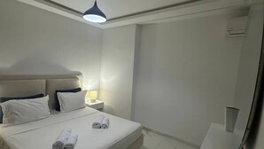 A hotel room with a bed, bedside lamp, and a desk with a chair. - Exceptional Apartment Luxury and Absolute Comfort (Tunis)