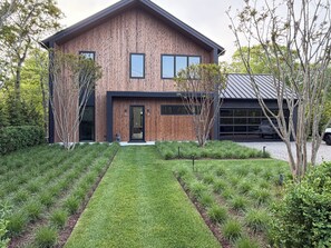 Ein modernes, zweistöckiges Haus mit Holzfassade, einer Haustür und einer Garage.