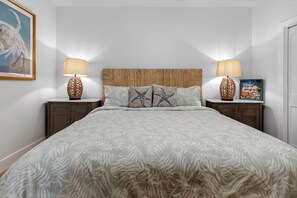 Ein Schlafzimmer mit einem Bett, zwei Nachttischen, einem Kopfteil, einem gerahmten Bild und zwei Lampen.