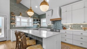 A kitchen with white cabinets, a large island, and pendant lighting. - True Beachfront New Build with Huge Oceanview Deck - Sans Souci Sleeps 12 (Port Aransas)
