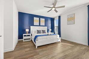A bedroom with a white bed, blue walls, a ceiling fan, and artwork on the walls. - Luxury Reunion Resort 6BR Villa Private Pool, Spa & Disney Nearby (Kissimmee)