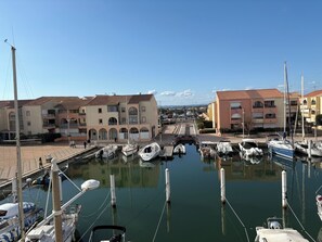 A marina with boats docked, buildings with balconies, and a clear sky. - Les Marines du Soleil in Carnon-Plage. (Mauguio)