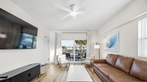 Ein modernes Wohnzimmer mit Flachbildfernseher, Sofa, Couchtisch und Deckenventilator.