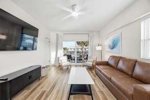 Ein modernes Wohnzimmer mit Flachbildfernseher, Sofa, Couchtisch und Deckenventilator.