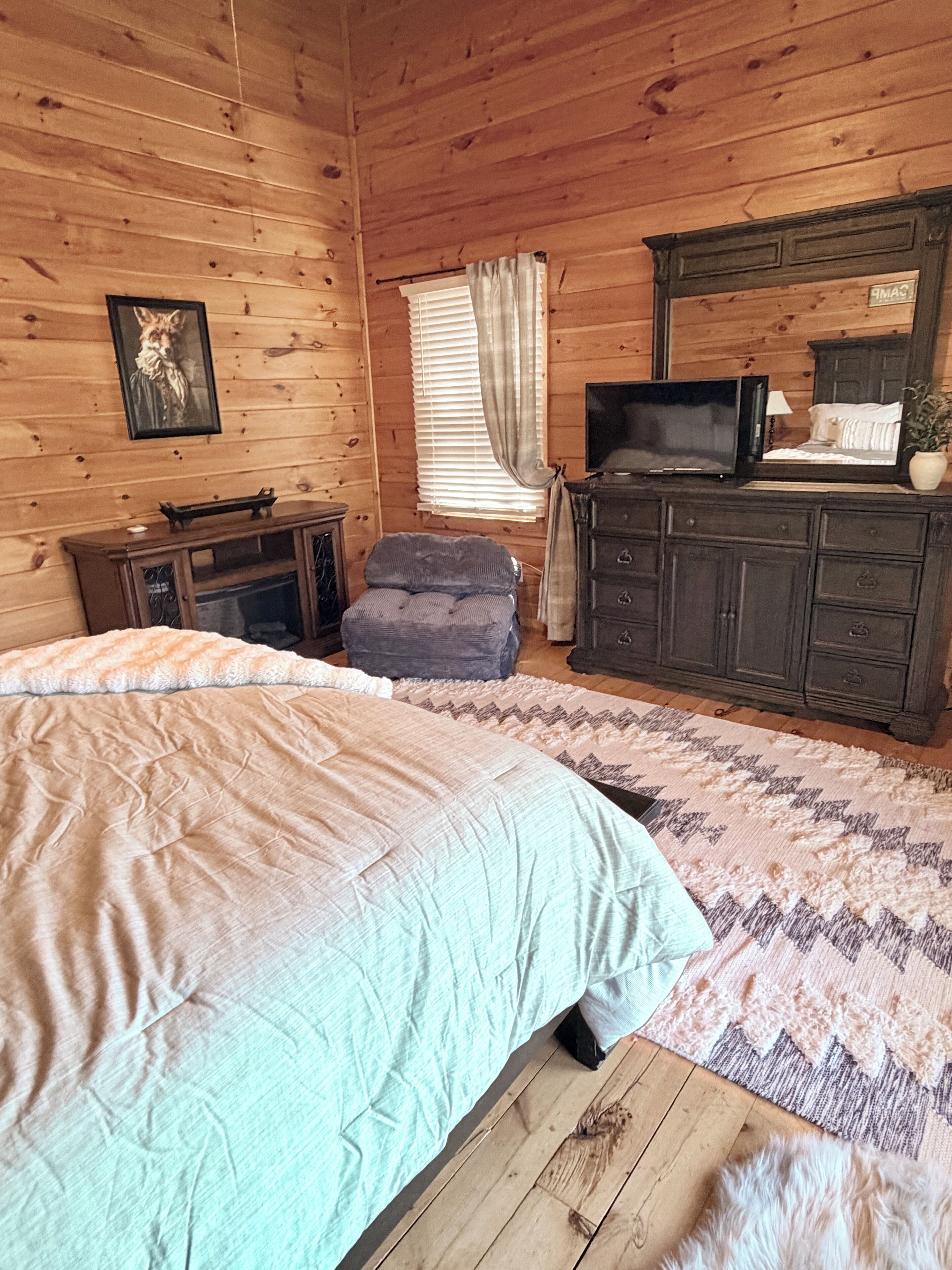 Une chambre dans une cabane en bois, comprenant un lit, une télévision, une commode et une chaise.