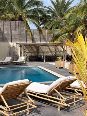 A pool area with lounge chairs, a wooden pergola, and palm trees. - Studio Ariba  2person studio in Jan Thiel with swimming pool (Jan Thiel)