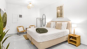 Une chambre à coucher comprenant un lit, une table de chevet, une lampe, des œuvres d’art murales et un miroir.