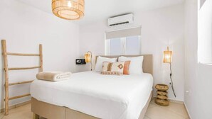 A bedroom with a bed, bedside lamps, an air conditioner, and a window. - Cas Agave 2bedroom apartment with swimming pool in Jan Thiel (Jan Thiel)