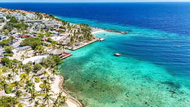 A coastal resort with clear turquoise waters, a beach, and a pier with umbrellas. - Cas Agave 2bedroom apartment with swimming pool in Jan Thiel (Jan Thiel)