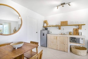 Eine kleine Küche mit Holztisch, Kühlschrank und Mikrowelle.