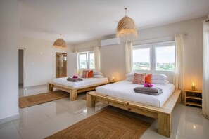 A modern bedroom with two wooden beds, large windows, and a view of the outdoors. - Casa Mei Mei – 8-person apartment in Jan Thiel with balcony (Jan Thiel)
