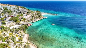 A coastal resort with clear turquoise waters, a beach, and a pier with umbrellas. - Casa Palm – 2-person apartment in Jan Thiel with pool (Jan Thiel)