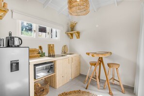 Eine kompakte Küche mit eingebautem Geschirrspüler, einer Kaffeemaschine, Holzbarhocker und einer Hängelampe.