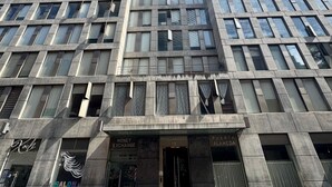 Ein mehrstöckiges Gebäude mit moderner Architektur, das einen markanten Eingang mit Beschilderung für verschiedene Geschäfte aufweist.