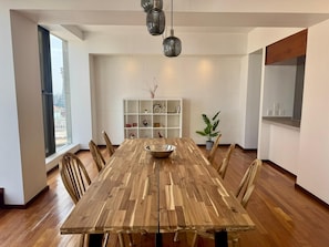 A dining area with a wooden table, chairs, a central bowl, a potted plant, and a white shelving unit with decorative items. - Dream Condo in the Heart of Mexico City (Ciudad de México)