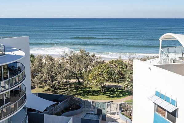 A modern building with a pool, a view of the ocean, and a garden area.