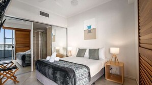 Ett modernt hotellrum med en stor säng, en spegel, ett litet sängbord och utsikt över balkongen.
