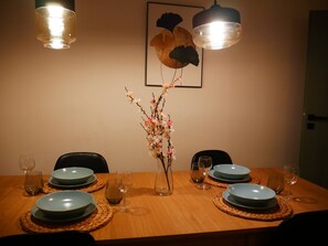 A dining table set with blue plates, wine glasses, and a vase with flowers. - Spacious Designer 4-room Apartment in Center (Warsaw)