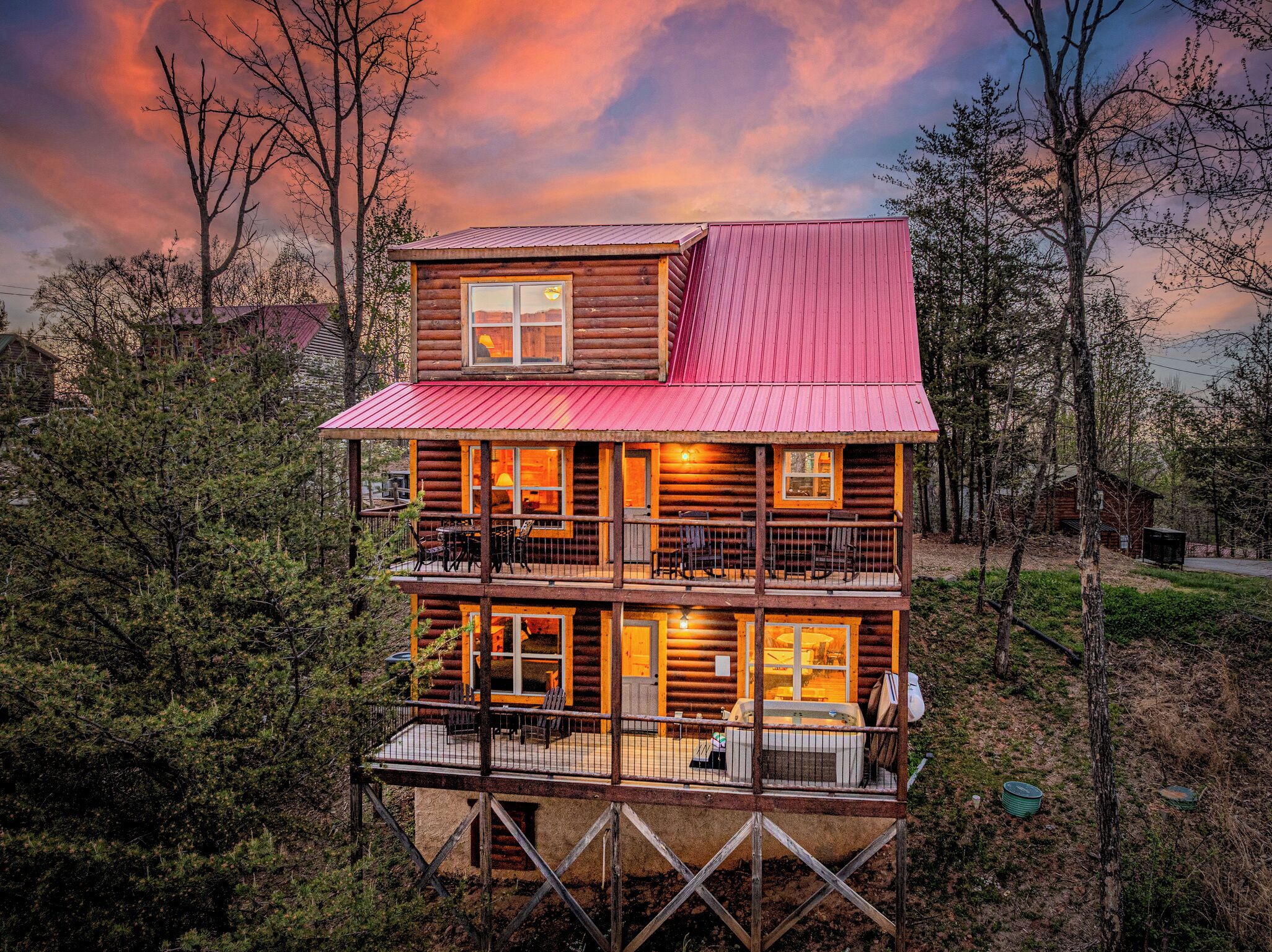 Una baita in legno a più piani con tetto rosso, diverse finestre e un balcone.