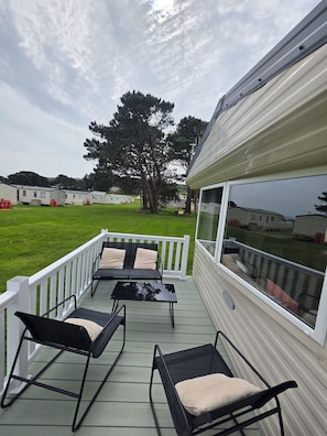 Une terrasse couverte avec des sièges extérieurs et une vue sur des maisons mobiles en arrière-plan.