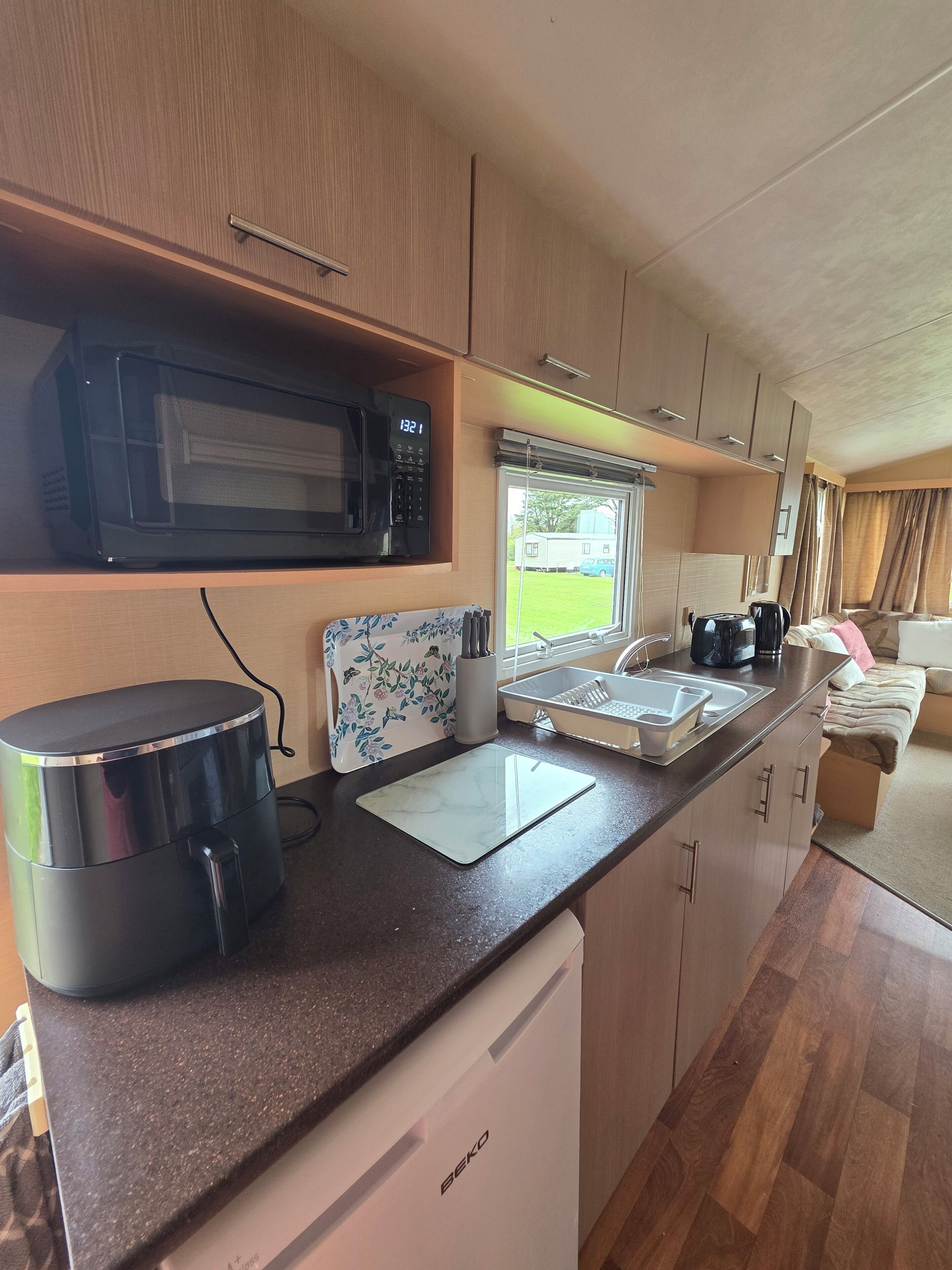 A compact kitchen with a microwave, kettle, and sink.