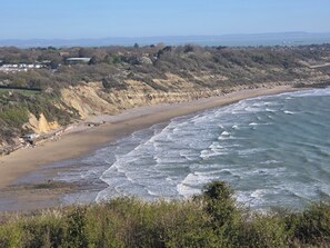 Eine Küstenlandschaft mit Strand, Klippen und weiter Blick aufs Meer.