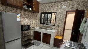 Eine kleine Küche mit Kühlschrank, Herd, Spüle und Holzschränken.