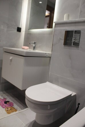 Un baño moderno con inodoro, lavamanos y espejo.