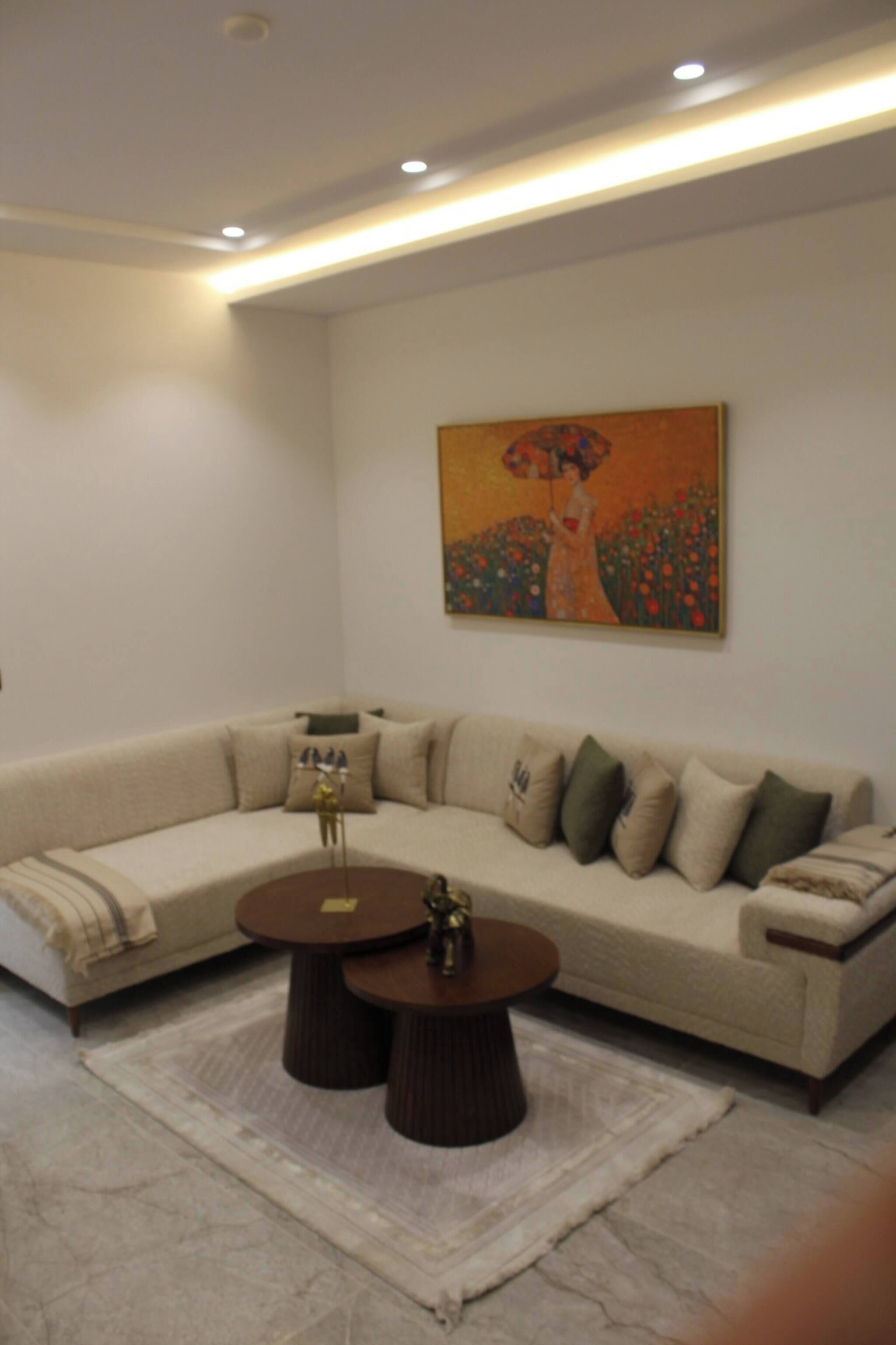 Una sala de estar moderna con un sofá seccional, dos mesas redondas de centro y un cuadro en la pared.