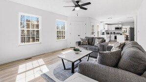 A modern living room with a sofa, coffee table, and a ceiling fan. - Luxury Fishers,IN Home - 4BR • Fully Renovated • Finished Basement • WiFi (Fishers)